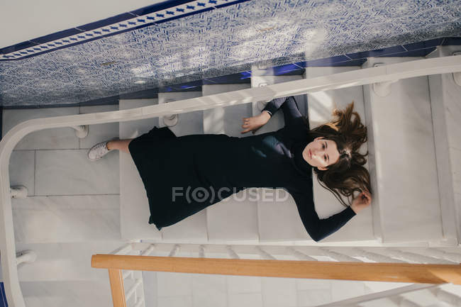 Blick von oben auf eine Frau, die auf Stufen liegt und in die Kamera blickt. — Stockfoto