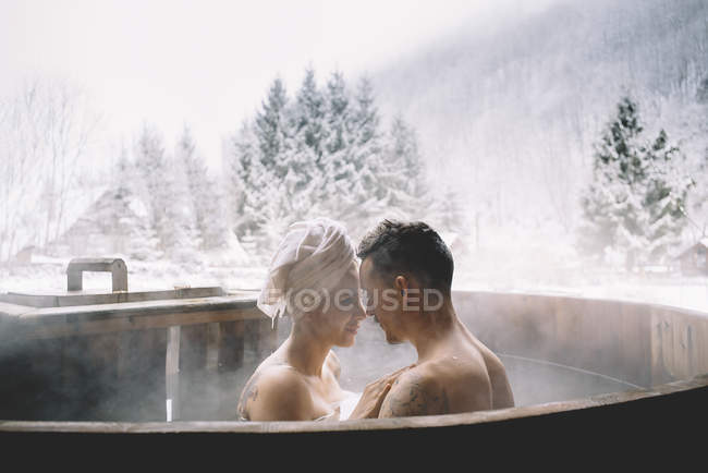 Sensual couple relaxing in plunge tub over winter landscape — Stock Photo