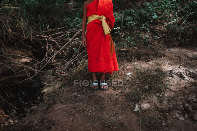 Crop  Buddhist monk in red clothes standing on hill in nature. — Stock Photo
