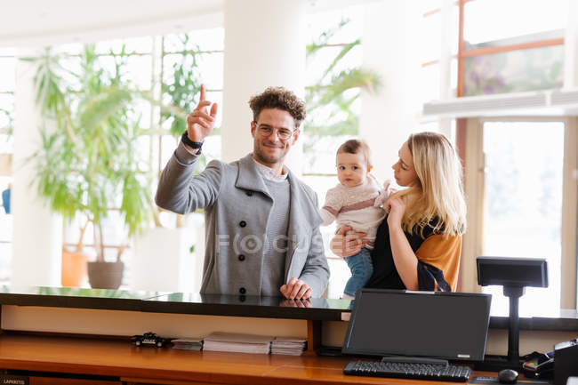 Glückliche Familie ruft Mitarbeiter während sie an der Rezeption im Hotel stehen. — Stockfoto