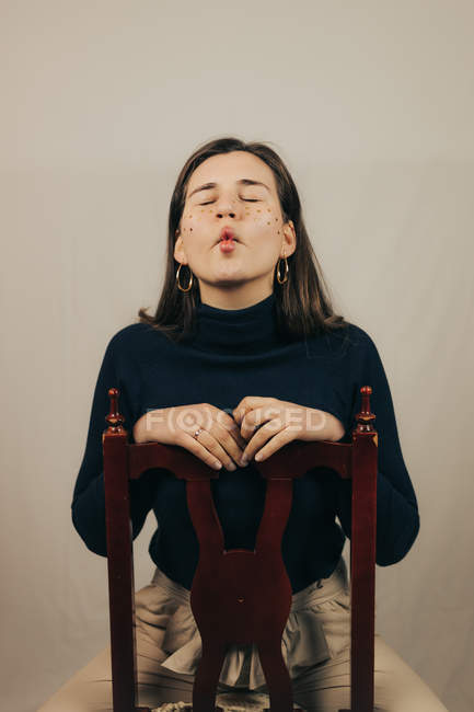 Bruna donna con brillantini sul viso seduta sulla sedia e smorzare — Foto stock