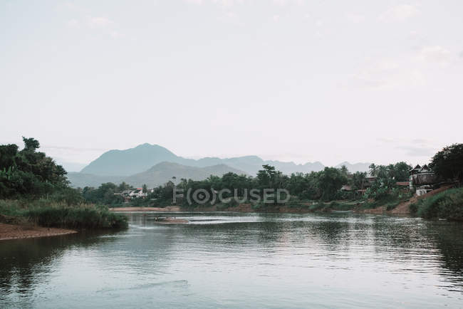 Pittoresca vista sul lago calmo con sponde verdi e colline lontane . — Foto stock
