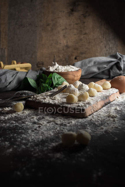 Сельский натюрморт сырых ньокки на разделочной доске за кухонным столом — стоковое фото