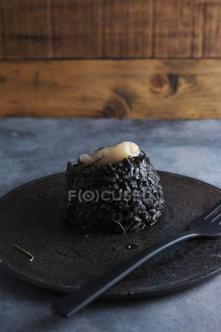 Schwarzer Reis mit Tintenfisch auf schwarzem Teller und Grunge-Hintergrund — Stockfoto
