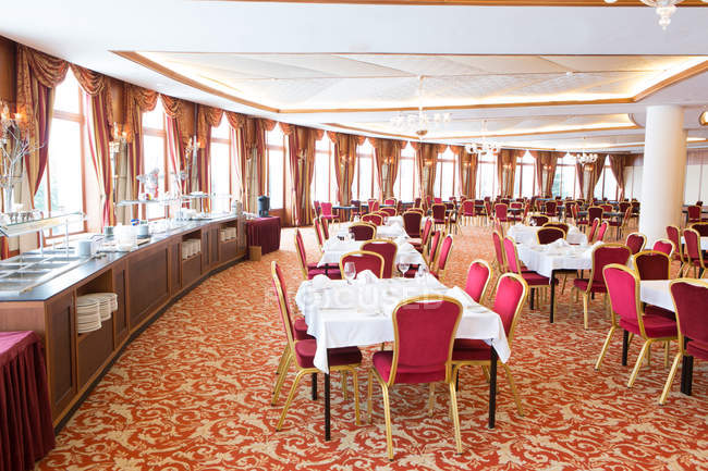 Vista interior de la gran sala de restaurante con mesas servidas - foto de stock
