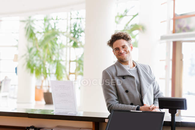 Улыбающийся мужчина в очках, стоящий у стойки регистрации в отеле . — стоковое фото