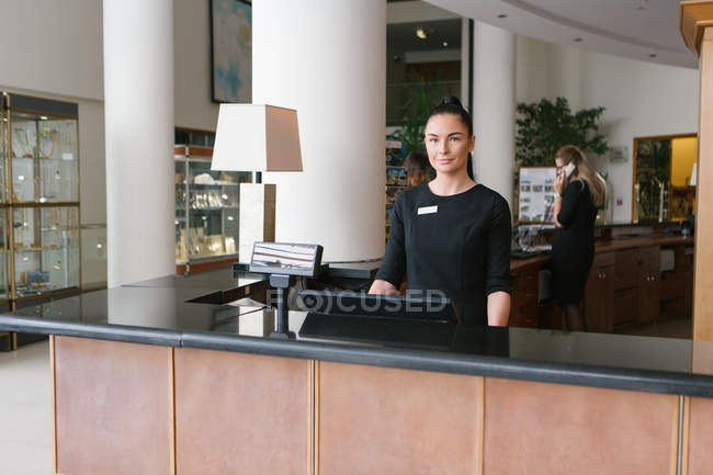 Pretty hotel worker standing in reception and looking at camera — Stock Photo
