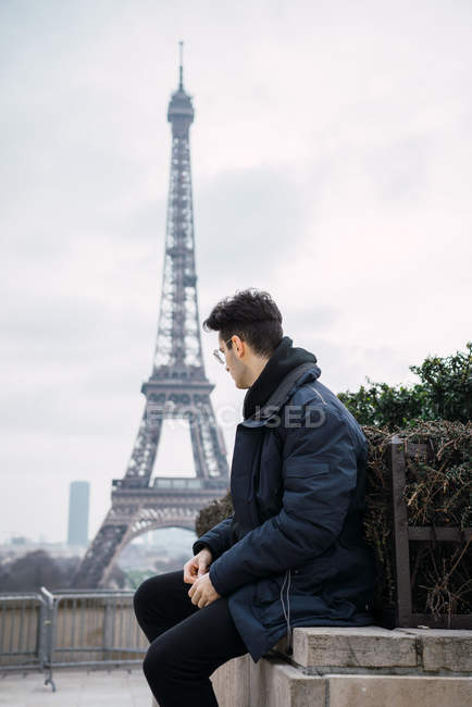 Young man resting on background of Eiffel tower. — Stock Photo