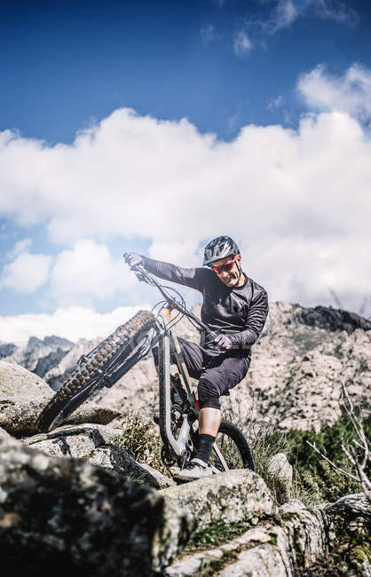 Велосипедист піднімає колесо гірського велосипеда, щоб піднятися на скелю — стокове фото