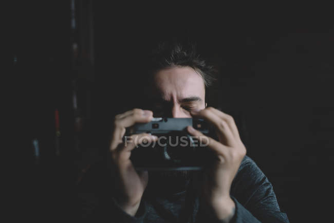 Fotógrafo posando con los ojos cerrados y sosteniendo la cámara vintage - foto de stock