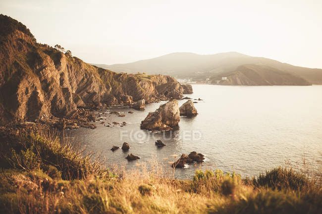 Vista a scogliere costiere e rocce in riva al mare alla luce del tramonto . — Foto stock