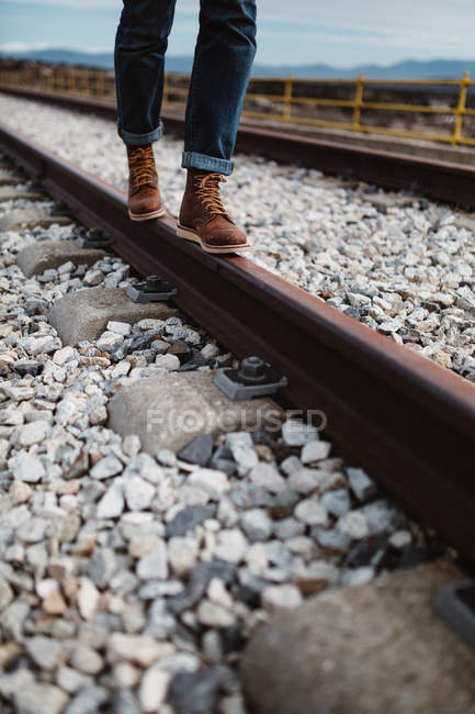 Section basse de la personne marchant et équilibrant sur rail rouillé dans la nature . — Photo de stock