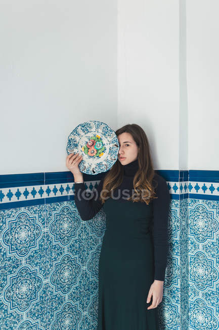 Jovem mulher bonita posando com placa colorida no fundo da parede azulejos azuis . — Fotografia de Stock
