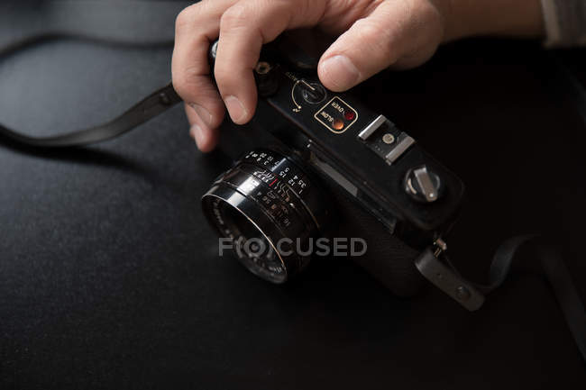 Taglia le mani regolando fotocamera vintage su sfondo nero — Foto stock