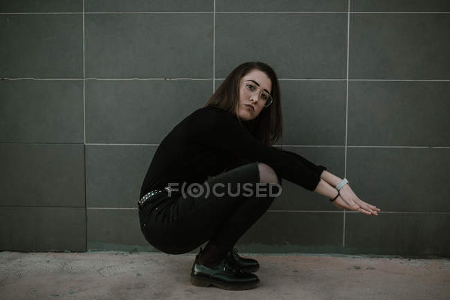 Seitenansicht einer Frau mit Brille auf Bunkern an grauer Wand. — Stockfoto