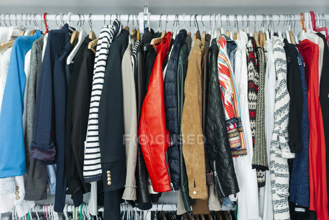Kleiderschrank mit verschiedenen stylischen Kleidungsstücken auf Kleiderbügeln — Stockfoto