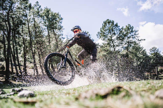 Radfahrer spritzt mit Mountainbike auf sonnenbeschienene Wiese — Stockfoto