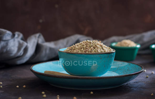 Крупный план керамических чаш, наполненных зерновыми и пшеничными хлопьями на столе — стоковое фото