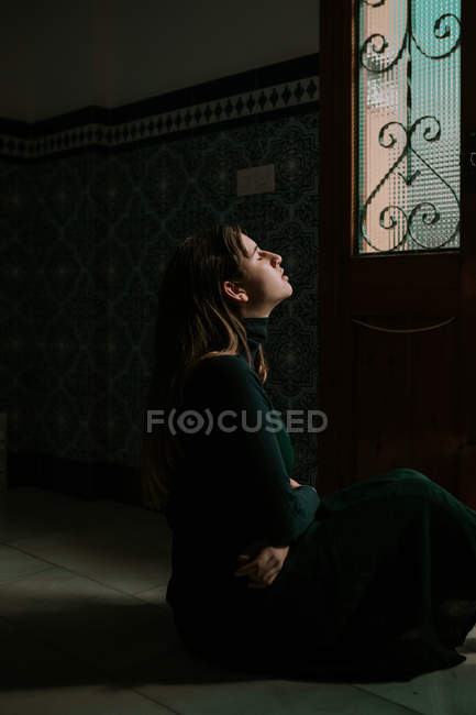 Vista laterale della donna sensuale seduta a terra alle porte con gli occhi chiusi — Foto stock