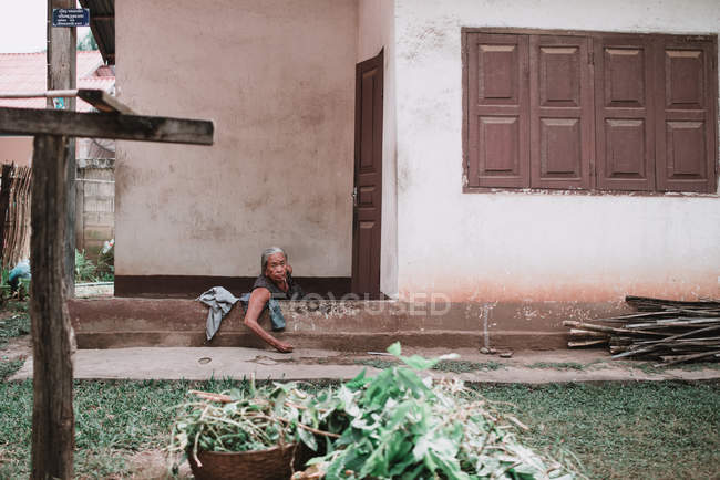 Laos, luang prabang: Seniorin sitzt im Hof und blickt in die Kamera. — Stockfoto
