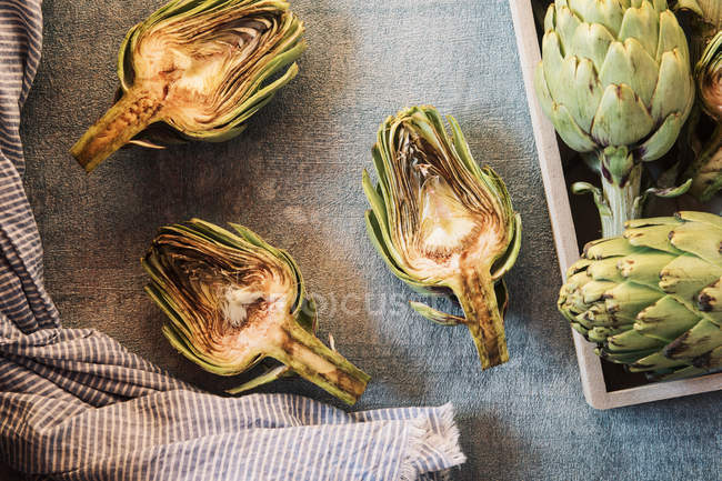 Top view rusty raw artichokes in blue background. — Stock Photo