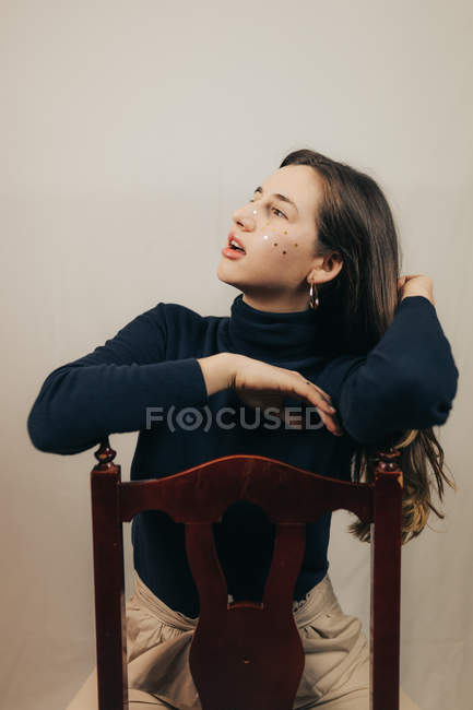 Brunette woman sitting on chair and and touching hair — Stock Photo