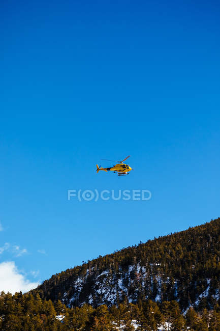 Helicóptero de resgate voando em montanhas sobre céu limpo — Fotografia de Stock