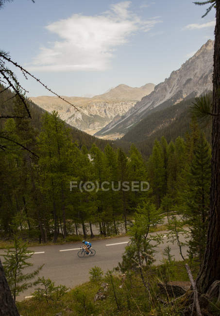 Radfahrer fährt auf asphaltierter Straße vor dem Hintergrund bewaldeter Berge — Stockfoto