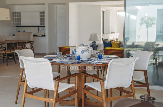 Interior de la vista a la mesa servida y sillas blancas en villa moderna . - foto de stock