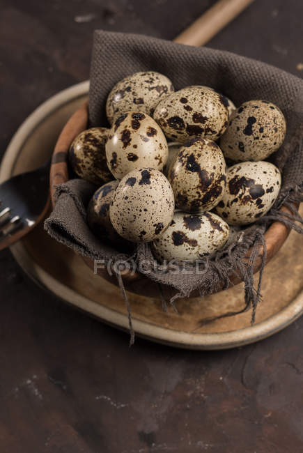 Still life of several eggs of quail in wooden bowl. — Stock Photo