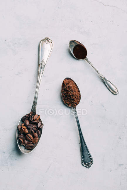 Direkt über der Ansicht von Kaffeebohnen und schwarzem Kaffee in Retro-Löffeln — Stockfoto