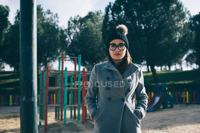 Mulher em roupas quentes elegantes e olhando para a câmera no playground . — Fotografia de Stock
