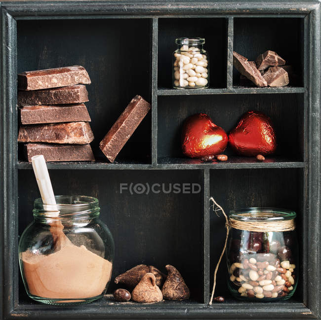 Wooden rustic box with various chocolates on shelves — Stock Photo