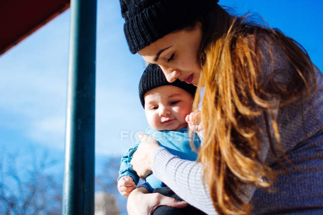 Madre con lindo niño en las manos en el parque - foto de stock