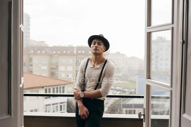 Handsome man leaning on balcony handrail and looking at camera — Stock Photo