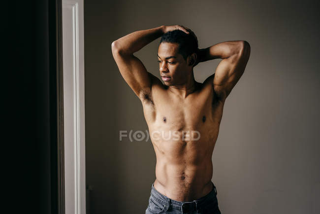 Shirtless homem negro posando com os braços levantados na janela — Fotografia de Stock