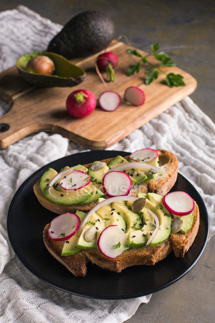 Still life of toast with avocado and radishes on table — Stock Photo