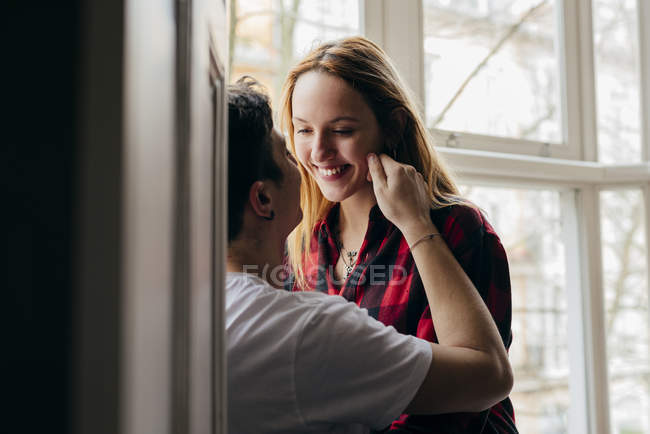 Fröhlicher junger Mann und Frau klebt zu Hause auf Fensterbank. — Stockfoto