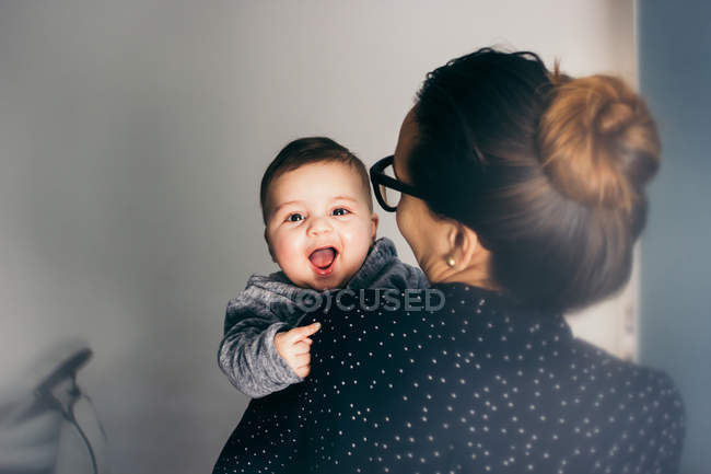 Adorable garçon sur les mains de la mère regardant caméra — Photo de stock