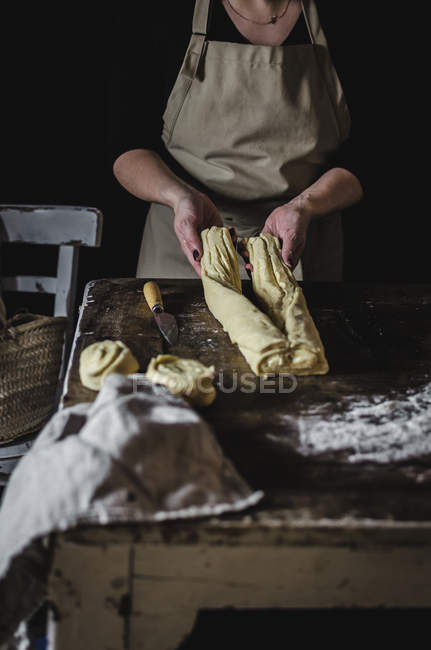 Sección media de la mujer preparando pastelería dulce en la mesa rural - foto de stock