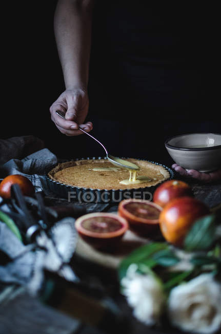 Crop female hand putting custard on tart — Stock Photo