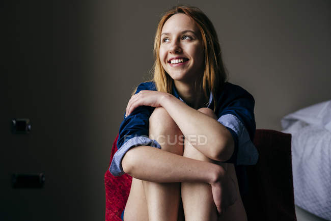 Cheerful blonde woman sitting in armchair and looking away — Stock Photo