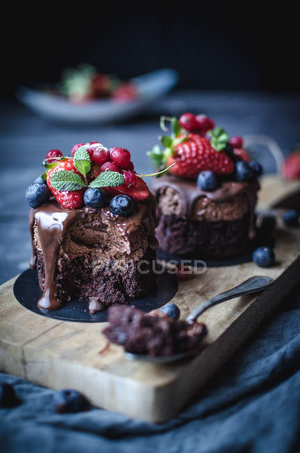 Still life of sweet cakes decorated with berries on wooden board — Stock Photo