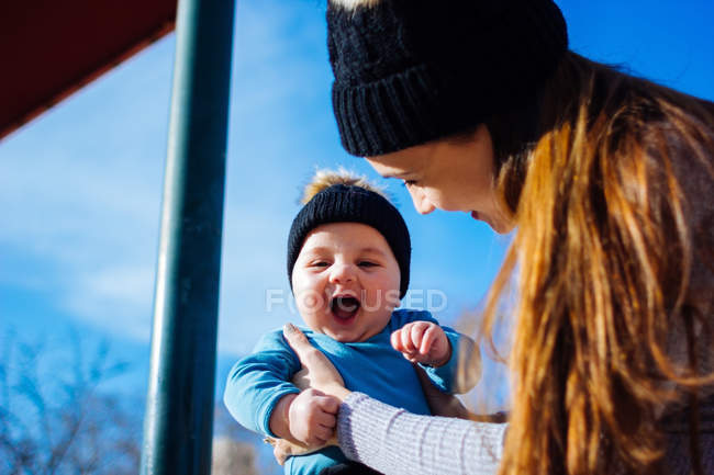 Mãe brincando com criança alegre em chapéu de malha — Fotografia de Stock