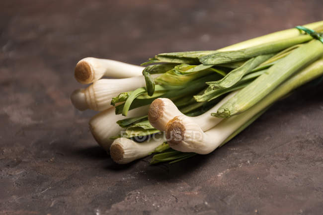 Cropped image of bunch of green garlic on table — Stock Photo