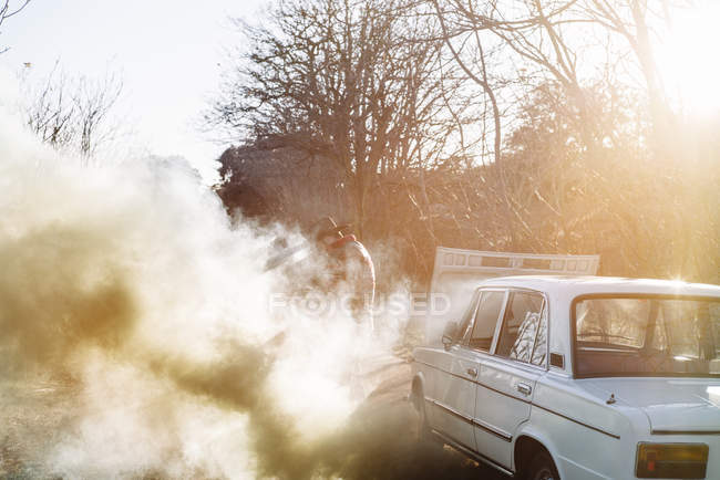 Vue latérale de l'homme adulte ouverture capot de fumer cassé voiture vintage dans la nature . — Photo de stock