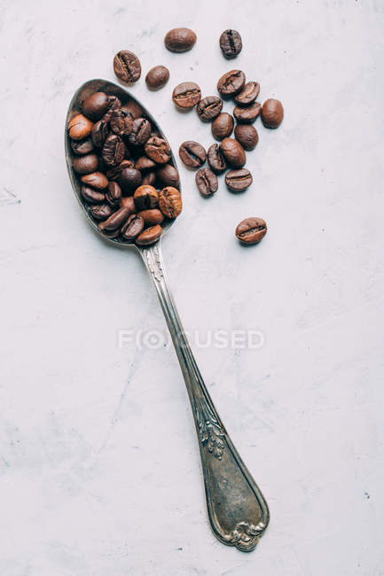Grains de café dans cuillère rétro sur fond blanc — Photo de stock