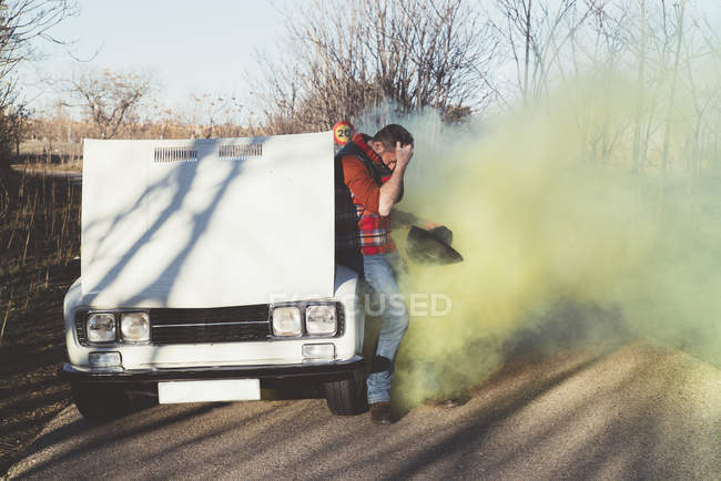Uomo appoggiato alla macchina che emette fumo e disperazione — Foto stock