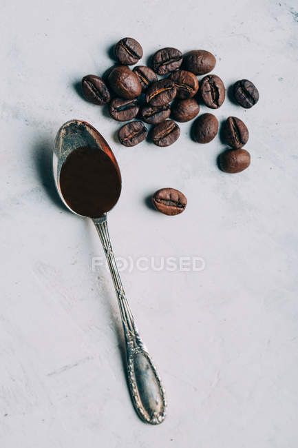 Black coffee in retro spoon by coffee beans — Stock Photo