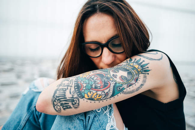 Donna sensuale con tatuaggi seduta sul marciapiede — Foto stock